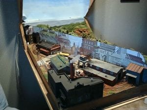 Model train layout on coffee table with diagonal divider. 