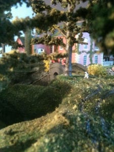 trees and a white dog in the woods of the model railroad layout