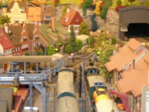 Model train moving through the city with railway signals.